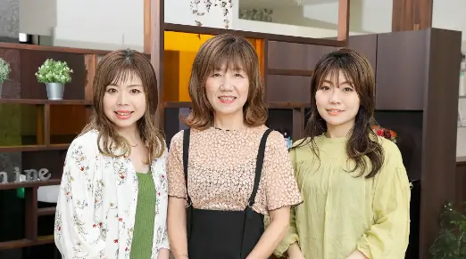 美容室shine【シャイン】のスタッフ、店長YASUYO、スタイリスト KAZUMI、アイリスト・ネイリスト・エステティシャンYOSHIKOが並んでいる写真
